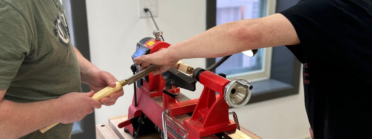 teacher helps student on lathe