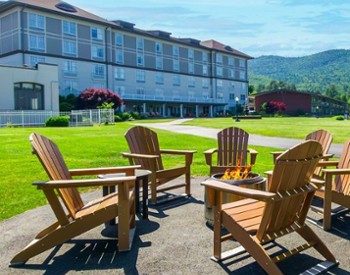 wooden adirondack chairs around a firepit with fort william henry hotel in the background