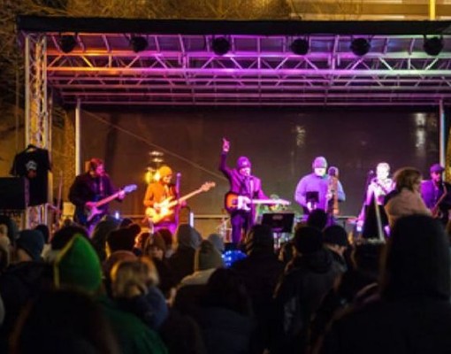 outdoor concert with musicians on stage and fans in crowd