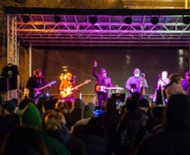 outdoor concert with musicians on stage and fans in crowd