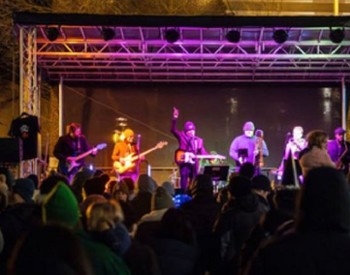 outdoor concert with musicians on stage and fans in crowd