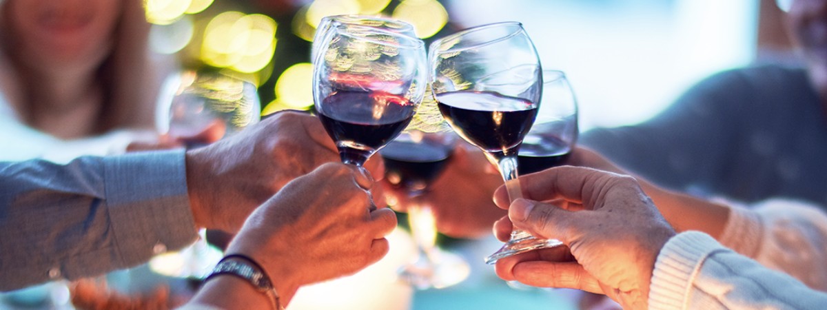 group of people cheersing glasses with red wine in them