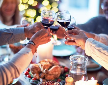 group of people cheersing glasses with red wine in them