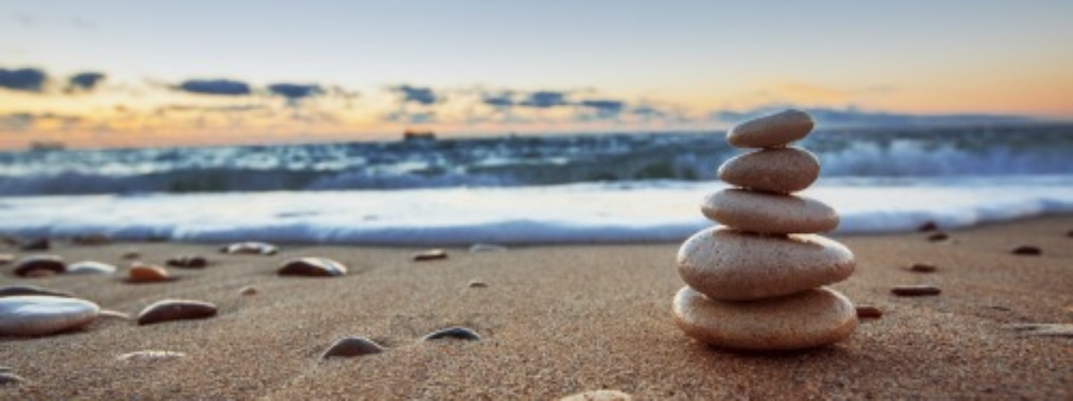 sandy beach with a cairn on the right side and the water and sky in the background