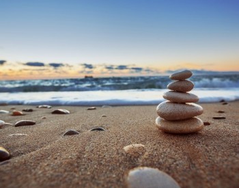 sandy beach with a cairn on the right side and the water and sky in the background