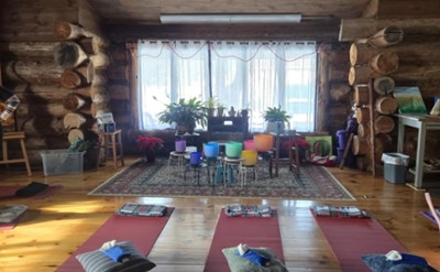 multi colored signing bowls on stands in a log cabin with yoga mats on the floor