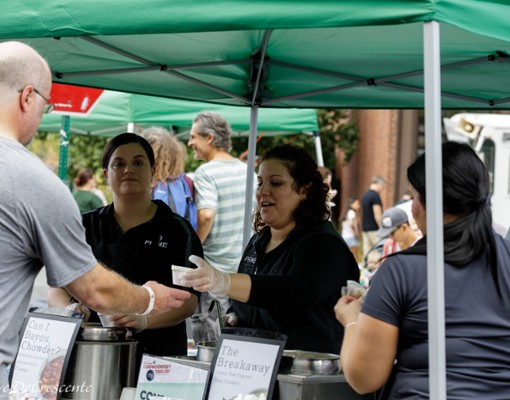 people getting chowder samples under a green umbrella