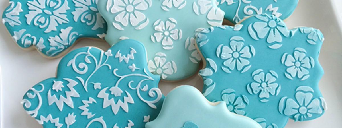 Teal colored cookies with stencilled floral patterns