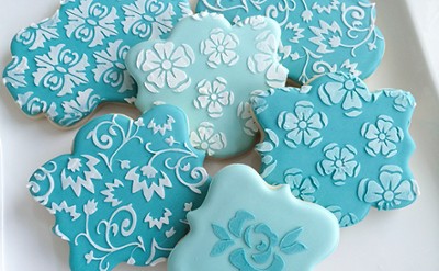 Teal colored cookies with stencilled floral patterns