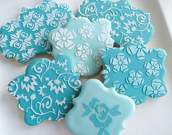 Teal colored cookies with stencilled floral patterns