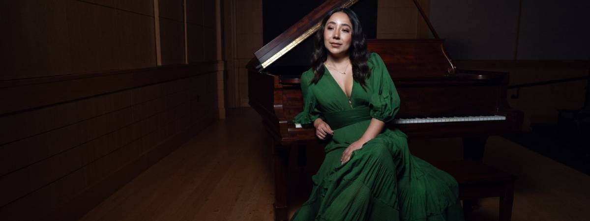 woman in green dress poses in front of piano