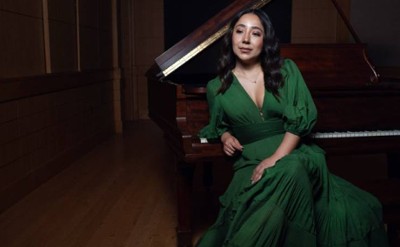woman in green dress poses in front of piano