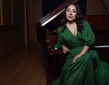 woman in green dress poses in front of piano