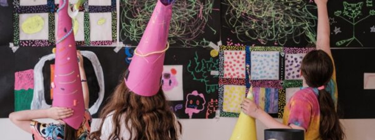 kids with handmade hats and art on the walls