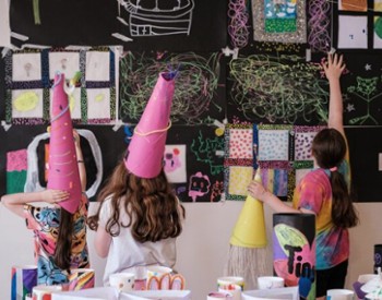 kids with handmade hats and art on the walls