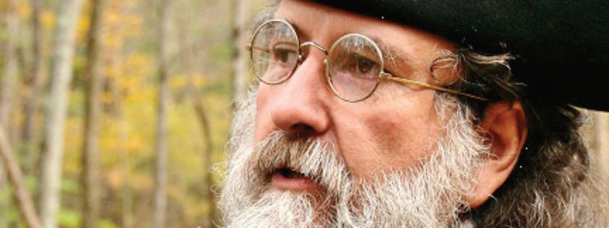 Photo of Dennis Picard. He is wearing a black tricorner hat, wire frame glasses and has a grey mustache and beard.