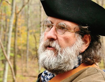 Photo of Dennis Picard. He is wearing a black tricorner hat, wire frame glasses and has a grey mustache and beard.