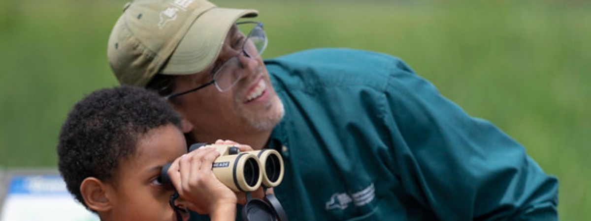 Five Rivers Educators showing a child how to use binoculars.
