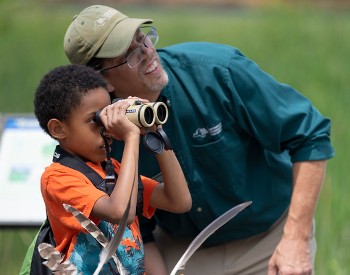 Five Rivers Educators showing a child how to use binoculars.