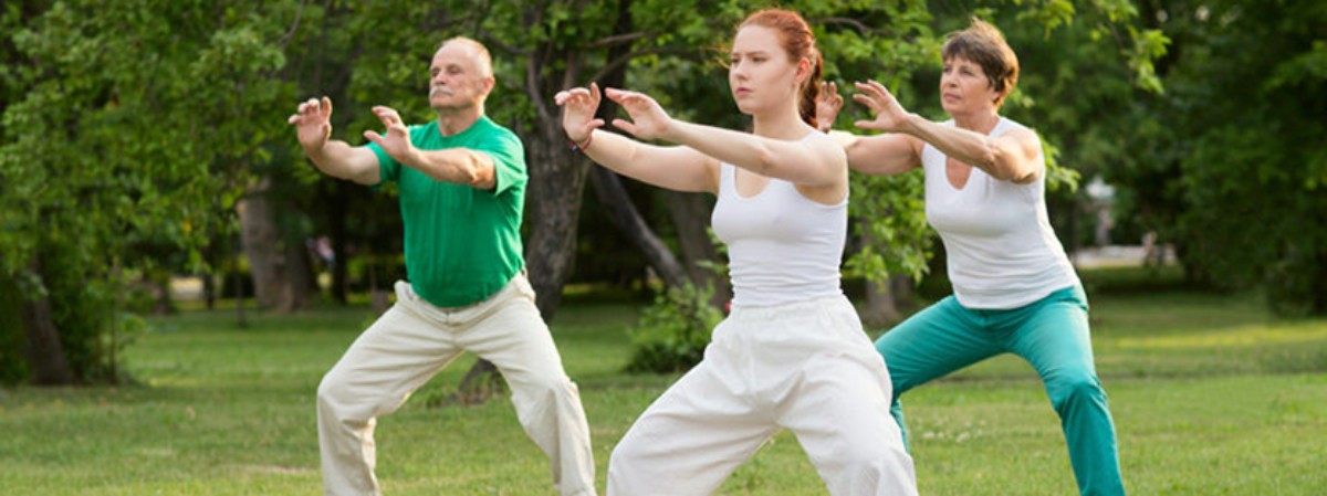 Three people outside moving in qigong