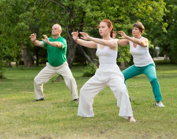 Three people outside moving in qigong
