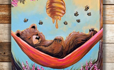 A bear sleeping in a hammock under a bee hive