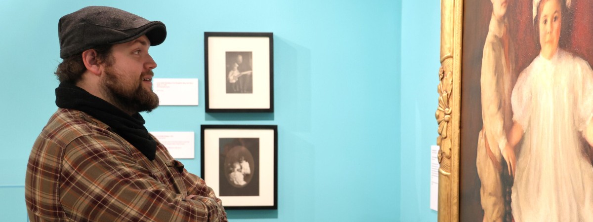 A man looks at a portrait of two children.
