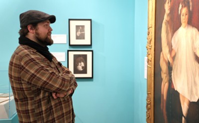 A man looks at a portrait of two children. 