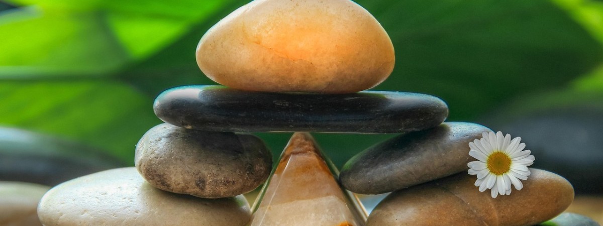 Photo of stacked stones in loose pyramid with a daisy