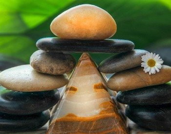 Photo of stacked stones in loose pyramid with a daisy