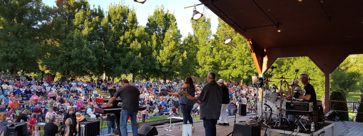 Large crowd in a park in front a pavilion style stage