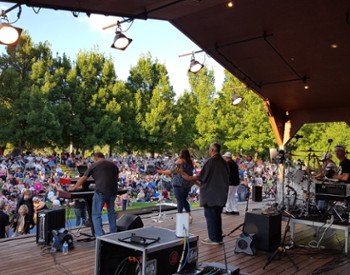 Large crowd in a park in front a pavilion style stage