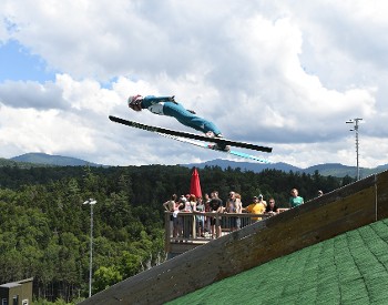 Ski Jumper soars into the air with spectators on the viewing deck.