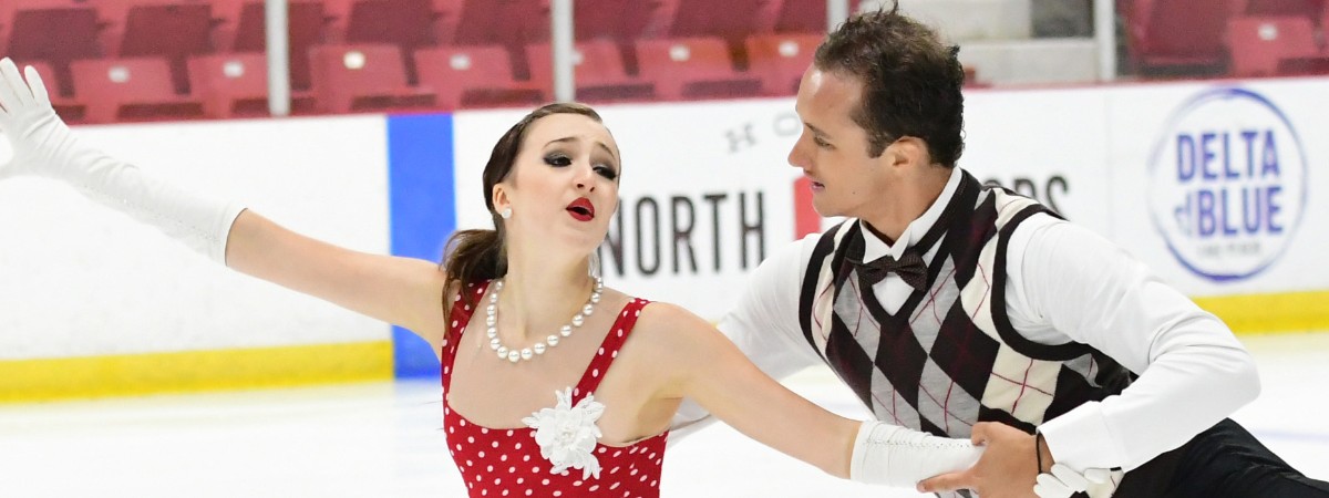Ice dance competitors skating across the ice in an artful way.