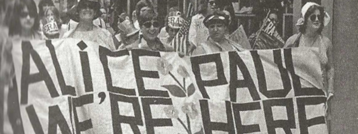 Suffragists carrying a banner