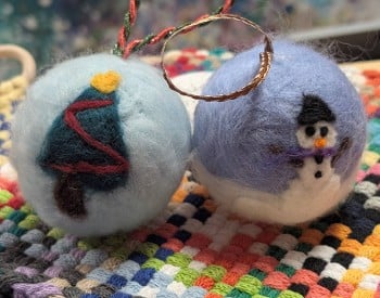 Two fuzzy ornaments, one with a holiday tree and one with a snowman
