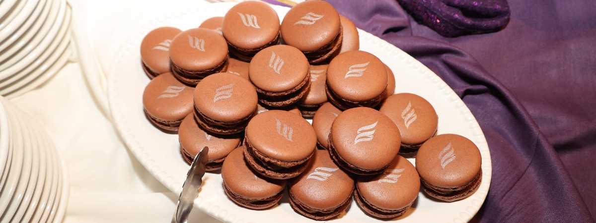 Chocolate macaroon pastries with EFNENY flame logo in silver on top