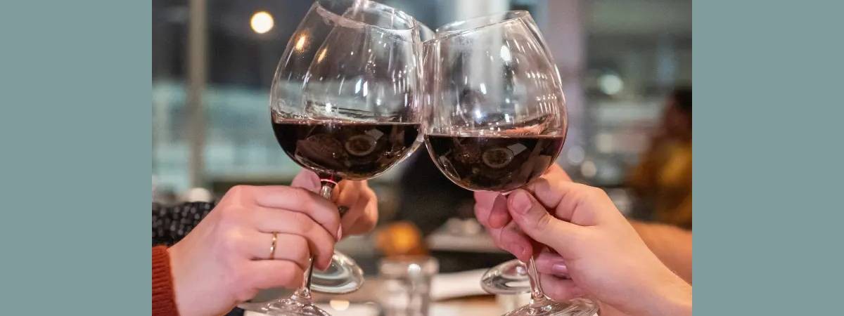 two wine glasses with red wine cheersing