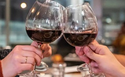 two wine glasses with red wine cheersing
