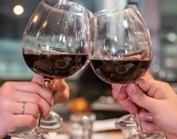 two wine glasses with red wine cheersing