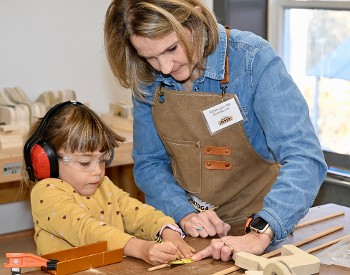 woodworking instructor helps a child measure her project