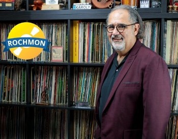Photo of the Rochmon! Chuck Vosganian standing in front of a huge record collection at Caff&egrave; Lena.