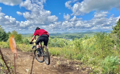 A mountain biker soars along a trail on a bright summer day