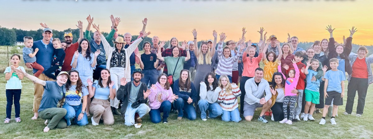 Community Members at Pitney Meadows Community Farm in a group picture in front of a sunset at the farm