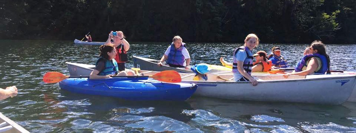 Friends in canoes and kayaks on Lakes Pond at Camp Little Notch