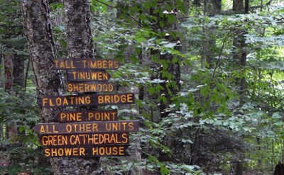wooden signs with camp unit names mounted on a tree