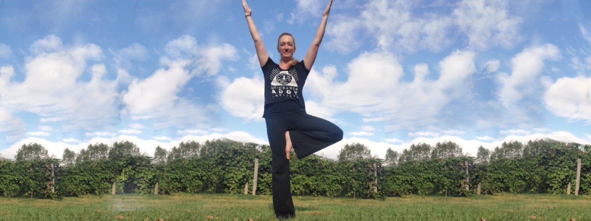 A woman standing in a Vineyard practicing yoga