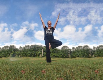 A woman standing in a Vineyard practicing yoga