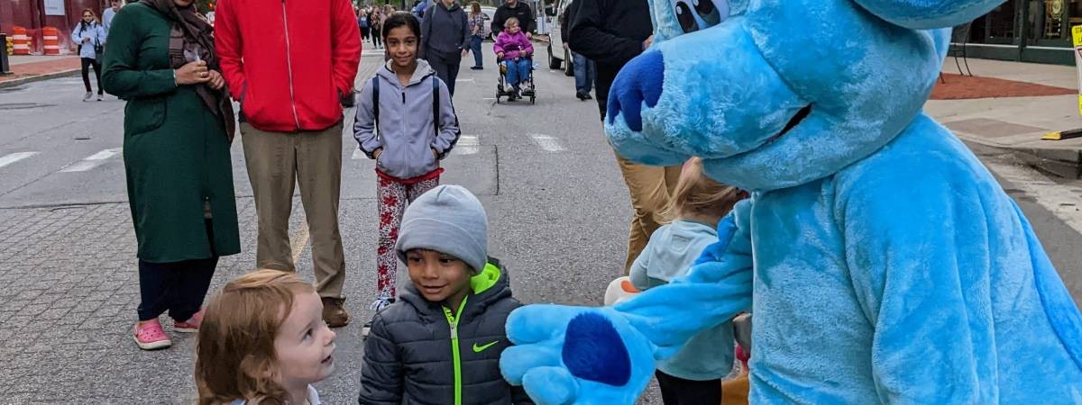 blue dog character high fives little girl