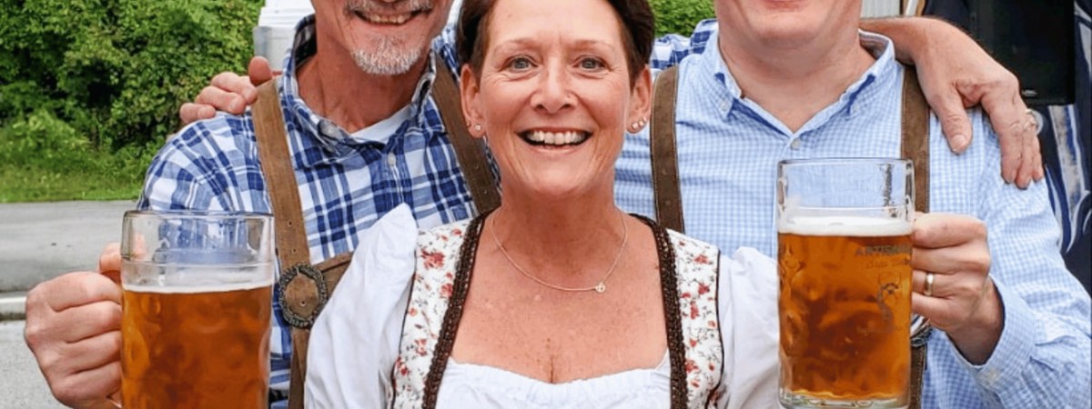 Guests in traditional Oktoberfest attire holding beer steins at Artisanal Brew Works in Saratoga Springs during an Oktoberfest celebration.